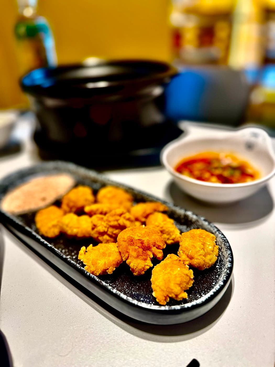 Salt and pepper chicken at Mr. Wang Hot Pot Oxford: crisp bite-sized pieces on a black platter with the pepper seasoning served on the side and a dipping sauce alongside