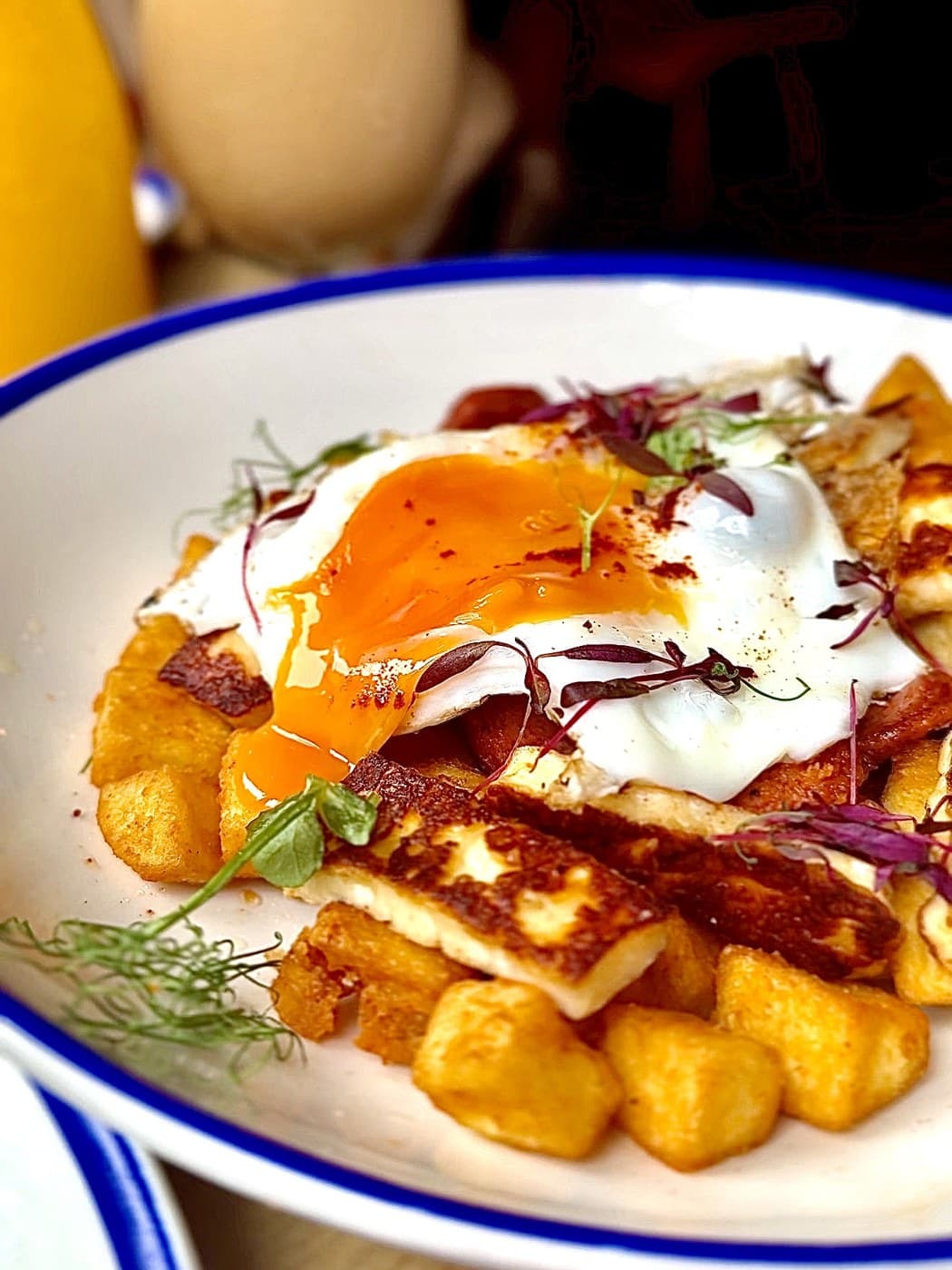 Papa's Plate at Oxford Brunch Bar close up: a runny-yolked fried egg over griddled halloumi, chorizo and golden home potatoes, with an iced coffee behind