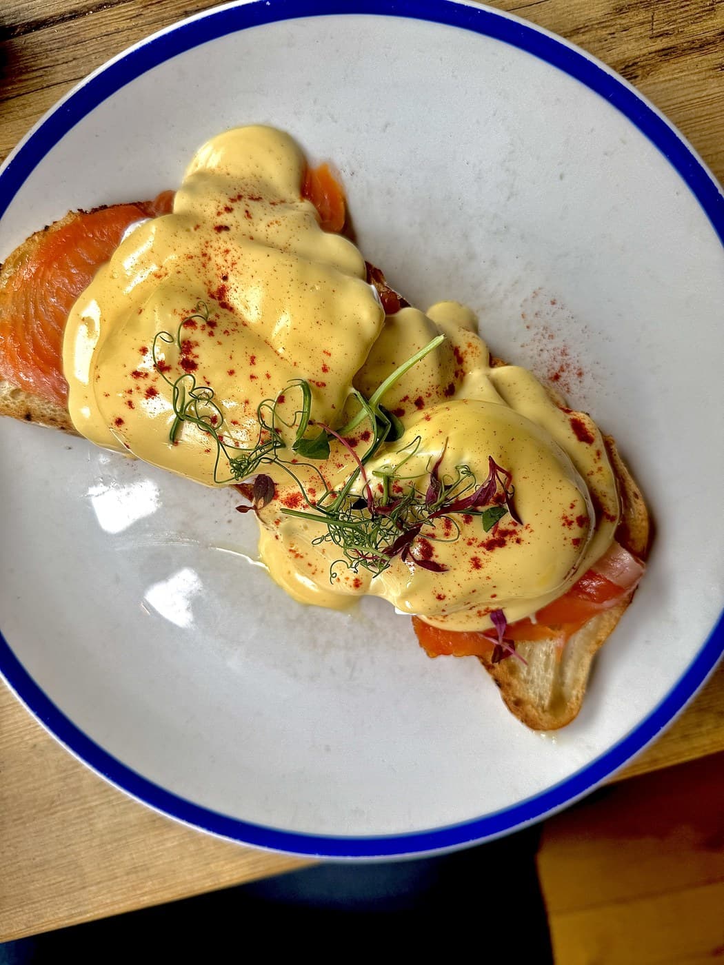 Egg Benedict with smoked salmon at Oxford Brunch Bar: poached eggs and smoked salmon on toasted Gatineau sourdough under a thick blanket of hollandaise, dusted with paprika and topped with micro herbs