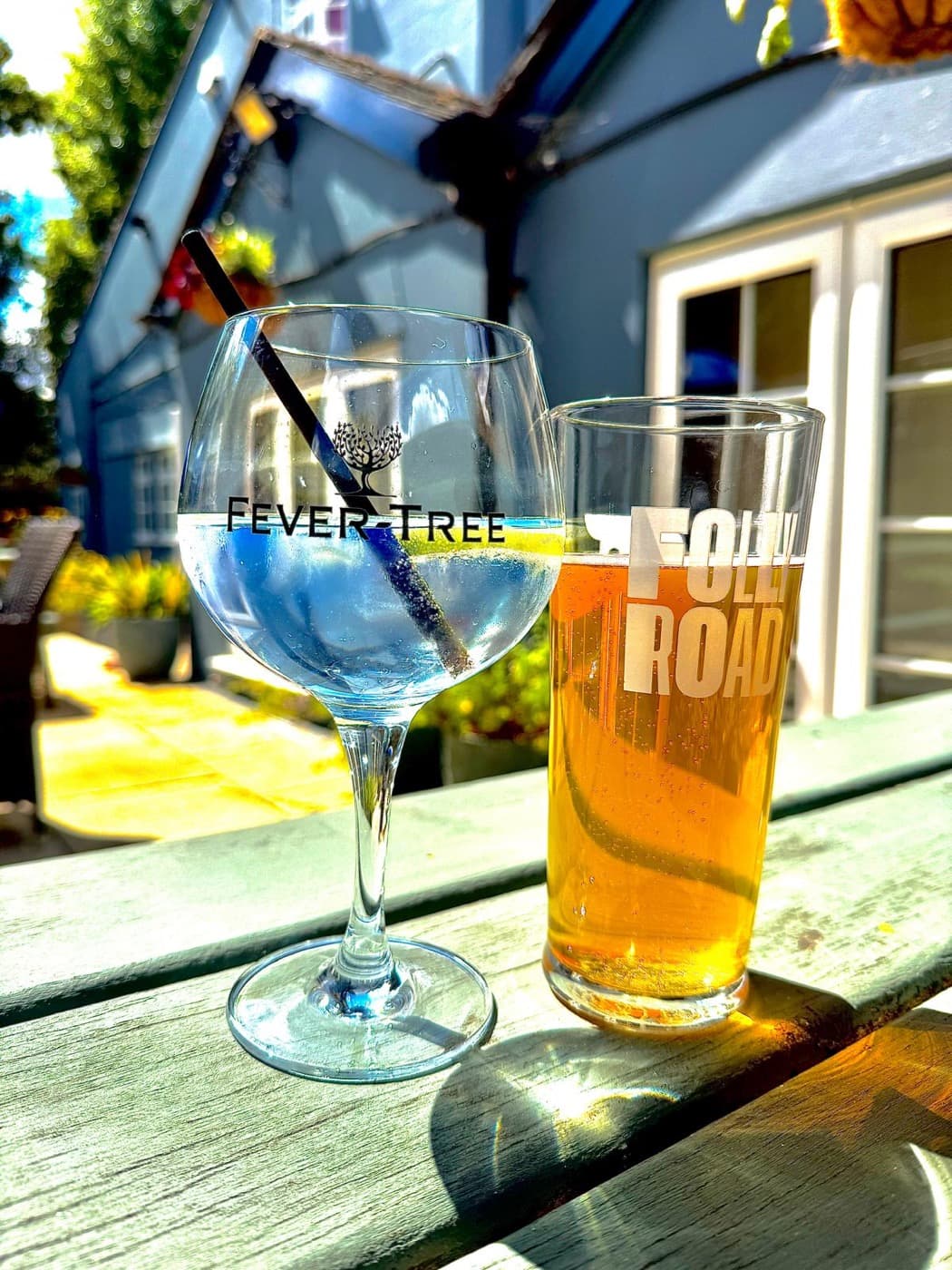 A gin and tonic and a pint of Folly Road on a garden table at The Prince of Wales Iffley