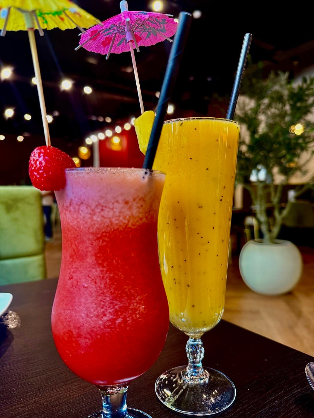 Two mocktails at Tempering, garnished with cocktail umbrellas and fresh fruit